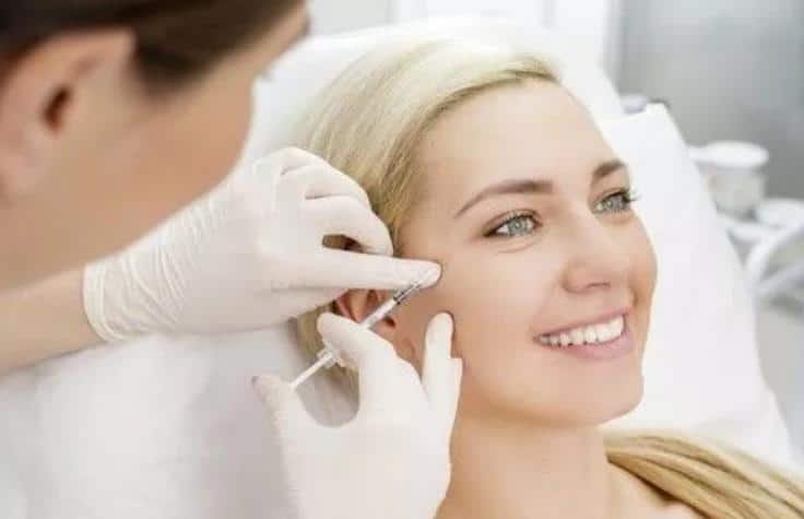 A woman getting fillers injected into her cheeks.